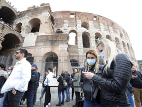 Visitors wearing protective face masks queue to enter the Colosseum in Rome, Italy, on Tuesday, Feb. 25, 2020.
