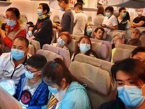 This picture taken on January 23, 2020 shows passengers wearing masks prepare to disembark from a flight from Hong Kong on arrival at Bangkok's airport ahead of the Chinese New Year in Bangkok on January 23, 2020.