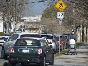 Pedestrians and vehicles navigate through traffic near the intersection of East 8th Avenue and Brunswick Street in Vancouver on Friday.