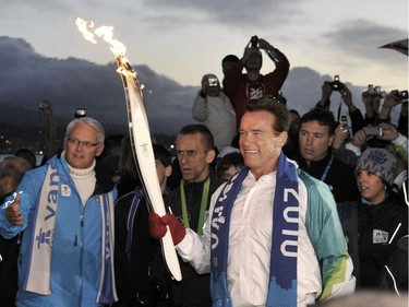 VANCOUVER, BC.:  FEBRUARY 12, 2010 - The Olympic torch is carried by California Governor Arnold Schwarzenegger  in Vancouver's Stanley Park Friday,  February 12, 2010 as the flame makes its final pass through the city on its way to the Opening Ceremony of the 2010 Winter Olympics. (Ian Lindsay/ PNG)   (For story by reporter)  [PNG Merlin Archive] B.C. Premier Gordon Campbell in blue jacket on left