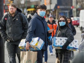Shoppers wear masks as they wait for public transit in Vancouver on Monday.