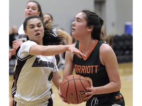Earl Marriott Mariners' Sydney Chapman tries to get past the relentless guarding of Heritage Woods Kodiaks' Jenna Griffin during Wednesday's action at the B.C. Secondary School Girls Basketball championship action at the Langley Event Centre.