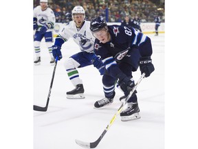 Winnipeg Jets Mason Appleton reaches for a loose puck while battling with Vancouver Canucks Guillaume Brisebois during NHL preseason hockey action at the Young Stars Classic held at the South Okanagan Events Centre in Penticton, BC, September, 8, 2017.