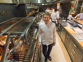 Andrew Richardson, executive chef at Elisa Steakhouse, pauses in front of his wood-fired grill as cooks prepare dishes on the “pass” for servers to pick up.