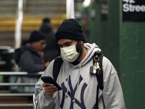 A man wearing a face mask uses his phone in the Times Square subway station, as people react to coronavirus disease (COVID-19) in New York City, U.S., March 19, 2020.