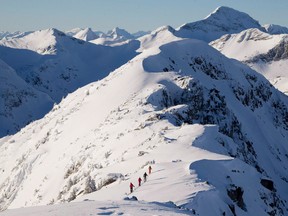 Backcountry skiers are dwarfed by the mountains as they make their way along a mountain ridge near McGillivray Pass Lodge located in the southern Chilcotin Mountains of British Columbia, on January 10, 2012. Rescue officials are asking backcountry users to choose low-risk activities as the risk for COVID-19 grows.