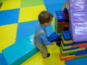 Boy playing with doll house in kindergarten.