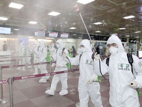 South Korean soldiers wearing protective gear spray disinfectant to help prevent the spread of the COVID-19 coronavirus, at the Daegu International Airport in Daegu on March 6, 2020.