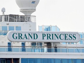 A man wearing a face mask looks out from aboard the Grand Princess cruise ship, operated by Princess Cruises, as it maintains a holding pattern about 25 miles off the coast of San Francisco, California on March 8, 2020. California prepared to disembark passengers from a virus-hit cruise ship as officials played down any risk to local communities. The Grand Princess, which has 21 novel coronavirus infections among the 3,500 people on board, is set to dock in Oakland Monday after four days held off the coast of nearby San Francisco.