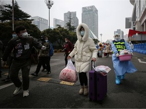 A patient (C) who has recovered from the COVID-19 coronavirus infection leaves a temporary hospital set up to treat people with the coronavirus in Wuhan in China's central Hubei province on March 9, 2020. - China closed most of its makeshift hospitals for coronavirus patients, some schools reopened and Disney resort staff went back to work on March 9 as normality slowly returns to the country after weeks battling the epidemic. (Photo by STR / AFP) / China OUT