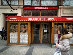 A pedestrian walks past a closed restaurant on the empty Champs-Elysees Avenue in Paris, France, on March 16, 2020,  as all non-essential public places including restaurants and cafes were closed to prevent the spread of COVID-19, caused by the novel coronavirus.