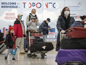 Travellers wearing masks walk through Toronto Pearson Airport amid continued concerns of the COVID-19 virus, March 16, 2020.