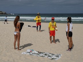 Surf rescue personnel enforce a closure of Bondi Beach after thousands of peopled flocked there in recent days, defying social distancing orders, in Sydney, Australia, March 21, 2020. (REUTERS/Loren Elliott)