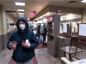 A customer leaves  Tim Hortons with takeout. The company closed all of its eating areas on Tuesday.