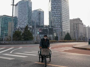A Chinese man wears a protective mask as he rides at empty street in March in Beijing, China. Retail sales in China fell 20 per cent.