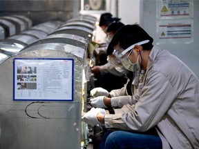 This photo taken on February 28, 2020, shows workers wearing facemasks polishing eyeglass frames at the Azure Eyeglasses Company in Wenzhou.