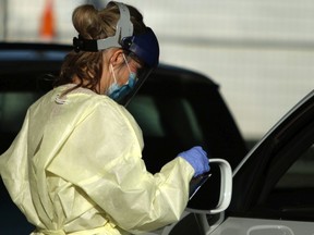 Nurse in full protective gear screens people at the COVID-19 drive-through testing clinic recently launched by Island Health in Victoria.