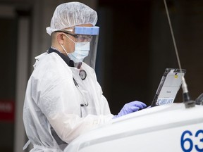 A B.C. ambulance paramedic works on a laptop outside Lions Gate Hospital in North Vancouver.