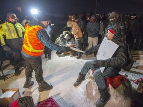 Police serve an injunction to protesters at a rail blockade in St-Lambert, south of Montreal on Thursday, February 20, 2020. As demonstrations continue across Canada in support of Wet'suwet'en hereditary chiefs opposing a pipeline through their territory, legal experts suggest it's time to reconsider how injunctions are employed when responding to Indigenous-led protests.THE CANADIAN PRESS/Ryan Remiorz