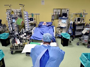 A member of the medical staff in a protective suit is seen Friday in front of a patient suffering from novel coronavirus in an intensive care unit at the San Raffaele hospital in Milan, Italy.