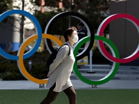 A woman wearing a protective face mask, following an outbreak of the coronavirus disease (COVID-19), walks past the Olympic rings in front of the Japan Olympics Museum in Tokyo.