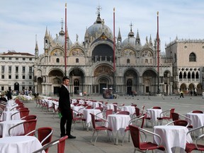 A waiter stands by empty tables outside a restaurant at St Mark's Square after the Italian government imposed a virtual lockdown on the north of Italy including Venice to try to contain a coronavirus outbreak, in Venice, Italy, March 9, 2020.