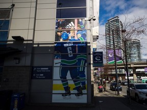 People walk outside Rogers Arena, home to the NHL's Vancouver Canucks, in Vancouver, on Thursday, March 12, 2020. The National Hockey league has suspended the season due to concerns about the coronavirus.