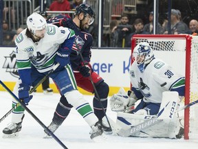 Columbus Blue Jackets left wing Nick Foligno (71) takes a shot on Vancouver Canucks goaltender Louis Domingue (30) as defenseman Christopher Tanev (8) defends during the second period at Nationwide Arena.