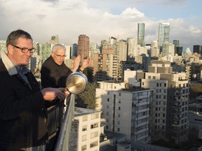 Reverend Gary Paterson, right, and his partner Tim Stevenson clap and beat on a pot with a wooden spoon as part of a tribute to health care workers in Vancouver, B.C. Tuesday, March 24, 2020. Thousands of people in Vancouver's west end have been going out on their balconies to applaud the front line heath care workers each night at 7pm.
