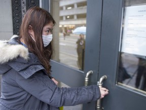 A student tries to enter University Canada West in Vancouver on  Thursday. The school is closing for three days for disinfection after two students were potentially exposed to the new coronavirus.