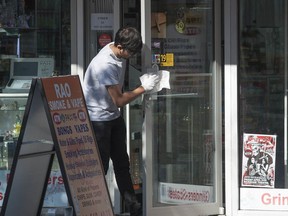 A clerk disinfects the handles of a door on a business on Granville Street.