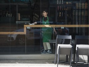 A Starbucks employee cleans up after the city of Vancouver ordered all restaurants and coffee shops closed to all but takeout and delivery service.