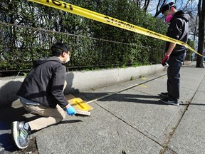 Workers paint yellow lines on the sidewalk to prevent the spread of Covid-19 in the lineup at The Door Is Open soup kitchen on Dunlevy St, in Vancouver BC., March 25, 2020.