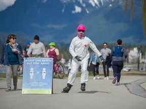 Andrey Murphy, who is skeptical of the COVID-19 hype mockingly wears at hazmat suit, a mask and gloves as he roller blades at Kits Beach.