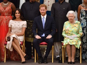 In this file photo taken on June 26, 2018 (L-R) Meghan, Duchess of Sussex, Britain's Prince Harry, Duke of Sussex and Britain's Queen Elizabeth II pose for a picture during the Queen's Young Leaders Awards Ceremony.