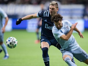 Vancouver Whitecaps' David Milinkovic, back left, and Sporting Kansas City's Graham Zusi vie for the ball during the first half of an MLS soccer game in Vancouver Feb. 29, 2020.