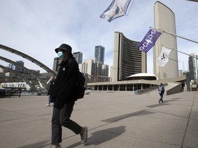 A small group of pedestrians pass through Nathan Phillips Square in front of Toronto City Hall as Torontonians adjust to the new normal.