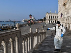 An employee of the municipal company Veritas sprays disinfectant in public areas on Ponte della Paglia in Venice on March 11, 2020, as part of precautionary measures against the spread of the new coronavirus COVID-19, a day after Italy imposed unprecedented national restrictions on its 60 million people Tuesday to control the deadly COVID-19 coronavirus.