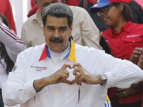 In this May 20, 2109 photo, Venezuela's President Nicolas Maduro flashes a hand-heart symbol to supporters outside Miraflores presidential palace in Caracas, Venezuela.