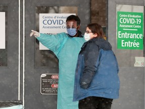 A nurse instructs a woman where to wait outside after providing her with a mask. A tent has been erected for people waiting outside the COVID-19 testing centre in Ottawa.