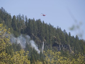 A helicopter drops a bucket of water on one of the several small fires burning on the hillsides above Squamish Valley Road.