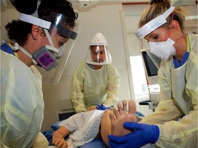 ICU clinical nurse educator Fiona McLeod participates in a training exercise with another nurse and a respiratory therapist at Surrey Memorial Hospital. They're all wearing personal protective equipment while working with a mock COVID-19 patient.