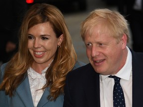 In this file photo taken on September 28, 2019 Britain's Prime Minister Boris Johnson walks with his partner Carrie Symonds as they arrive at The Midland, near the Manchester Central convention complex in Manchester, northwest England, on the eve of the annual Conservative Party conference.