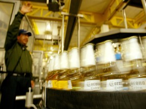 Bottles of Mexico's world famous Corona beer speed past a worker in the bottling line of Mexico City's Modelo brewery May 19, 2004.