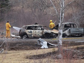 APRIL 20: A Wentworth, Nova Scotia, volunteer firefighter douses hotspots near destroyed vehicles linked to the deadly shooting rampage.