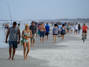 People walk down the beach on April 19, 2020 in Jacksonville Beach, Florida.