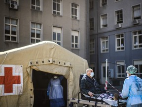 A health worker pushes a man on a stretcher towards a triage tent for suspected COVID-19 patients outside the Santa Maria Hospital in Lisbon on April 2, 2020.