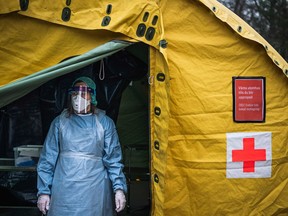 A medical staffer at Sophiahemmet hospital stands at the entrance of a tent for testing and receiving potential coronavirus COVID-19 patients on April 7, 2020 in Stockholm.