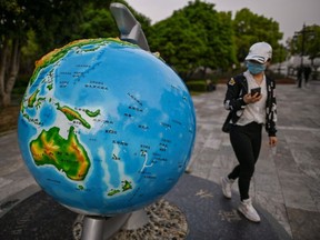 A woman wearing a facemask looks at a globe in a park in Wuhan. Thousands of Chinese travellers rushed to leave COVID-19 coronavirus-ravaged Wuhan this week as authorities lifted a more than two-month prohibition on outbound travel from the city where the global pandemic first emerged.