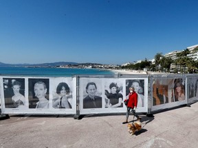 A woman walks past photos of the Cannes festival on the Croisette in Cannes as a lockdown is imposed to slow the rate of the coronavirus disease in France, March 18, 2020.